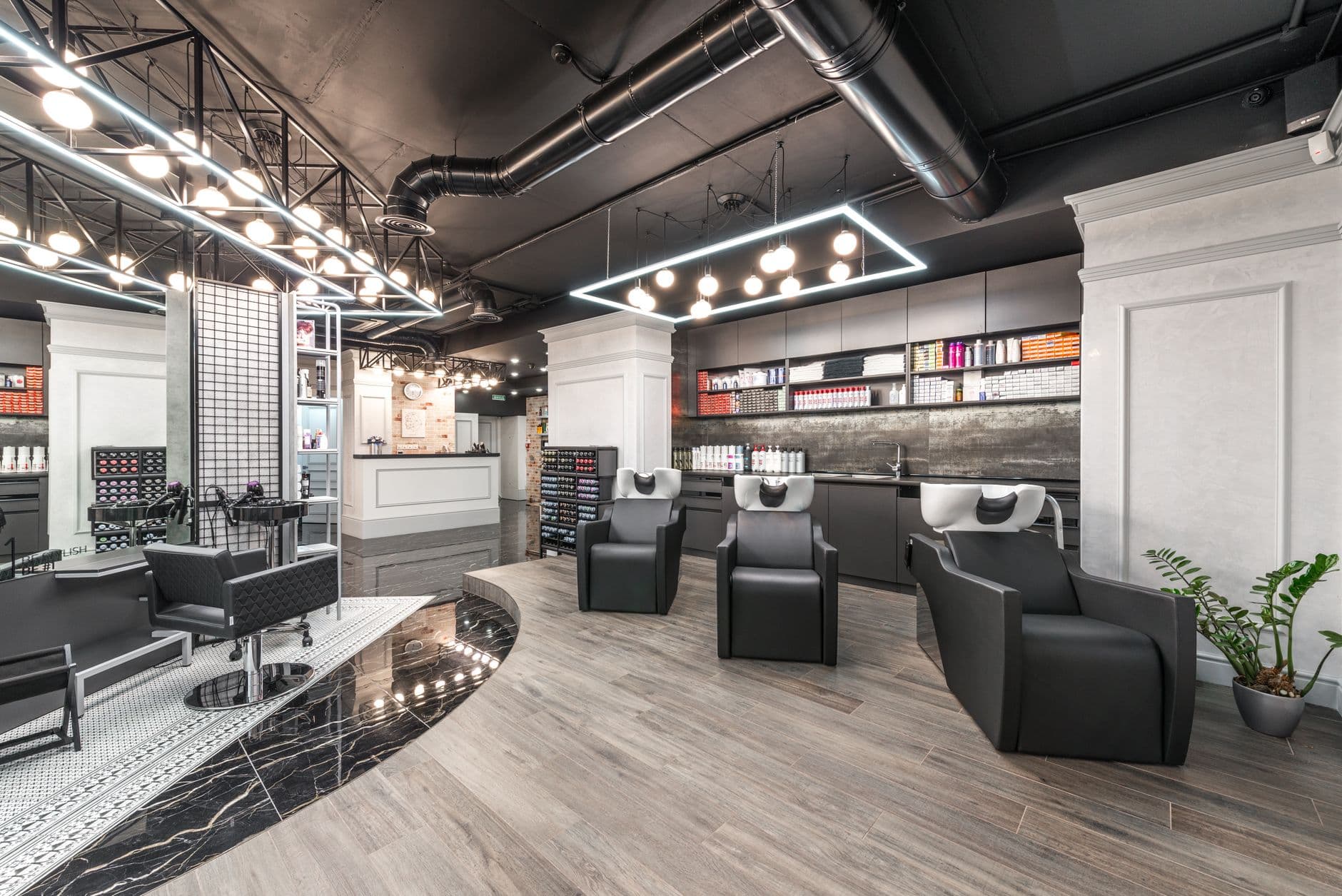 Stock photo of a modern hair salon interior with styling chairs, wash stations and product shelves
